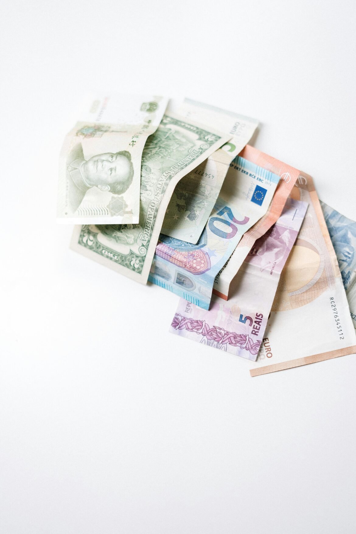 A diverse collection of international banknotes arranged on a white surface, showcasing global currencies.