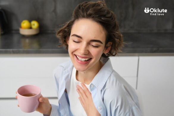 Person holding a pink mug and touching their chest while wearing a light blue shirt